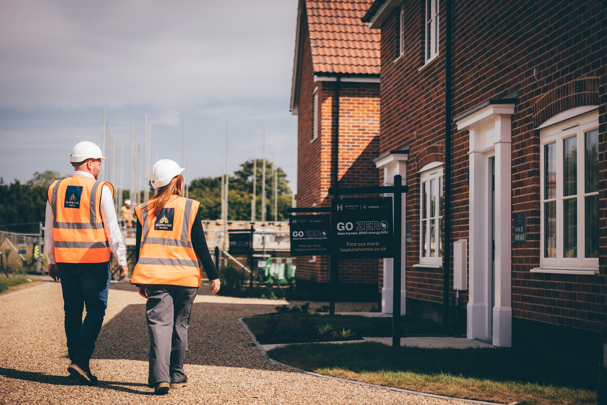 People in hard hats and high vis walking in front of new build homes